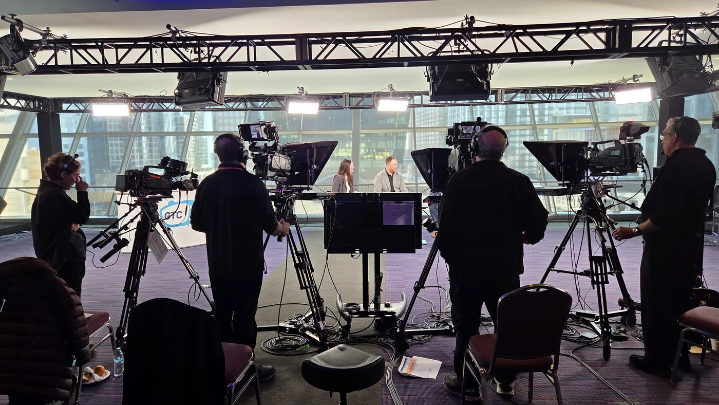 Stagedge crew operating broadcast cameras around a two-person interview set built at a conference venue