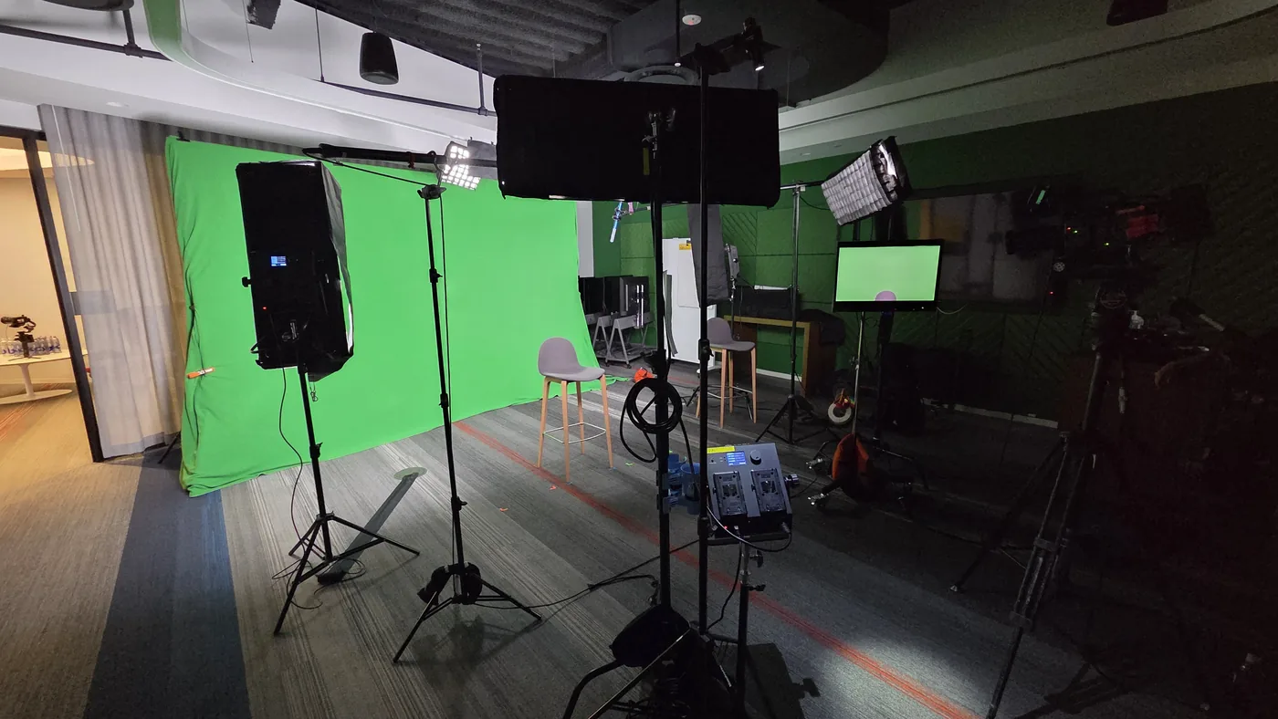 Portable green screen, lighting, and monitors set up for interviews in a client conference room