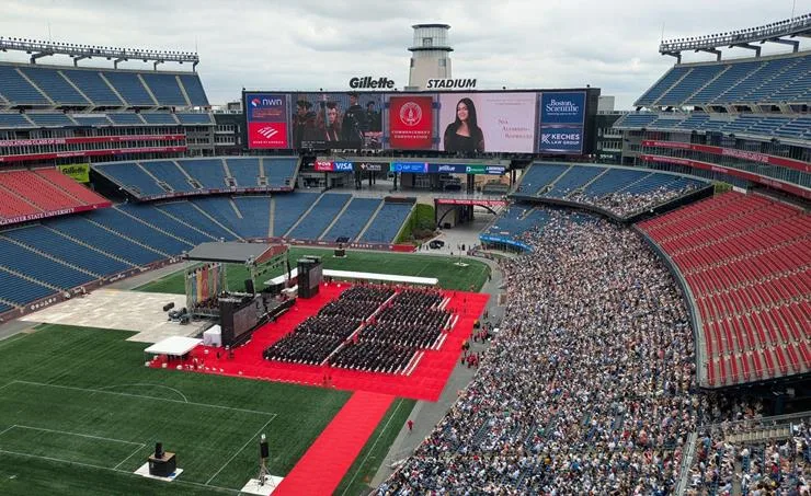 Graduates and stage setup at Bridgewater State University commencement at Gillette Stadium